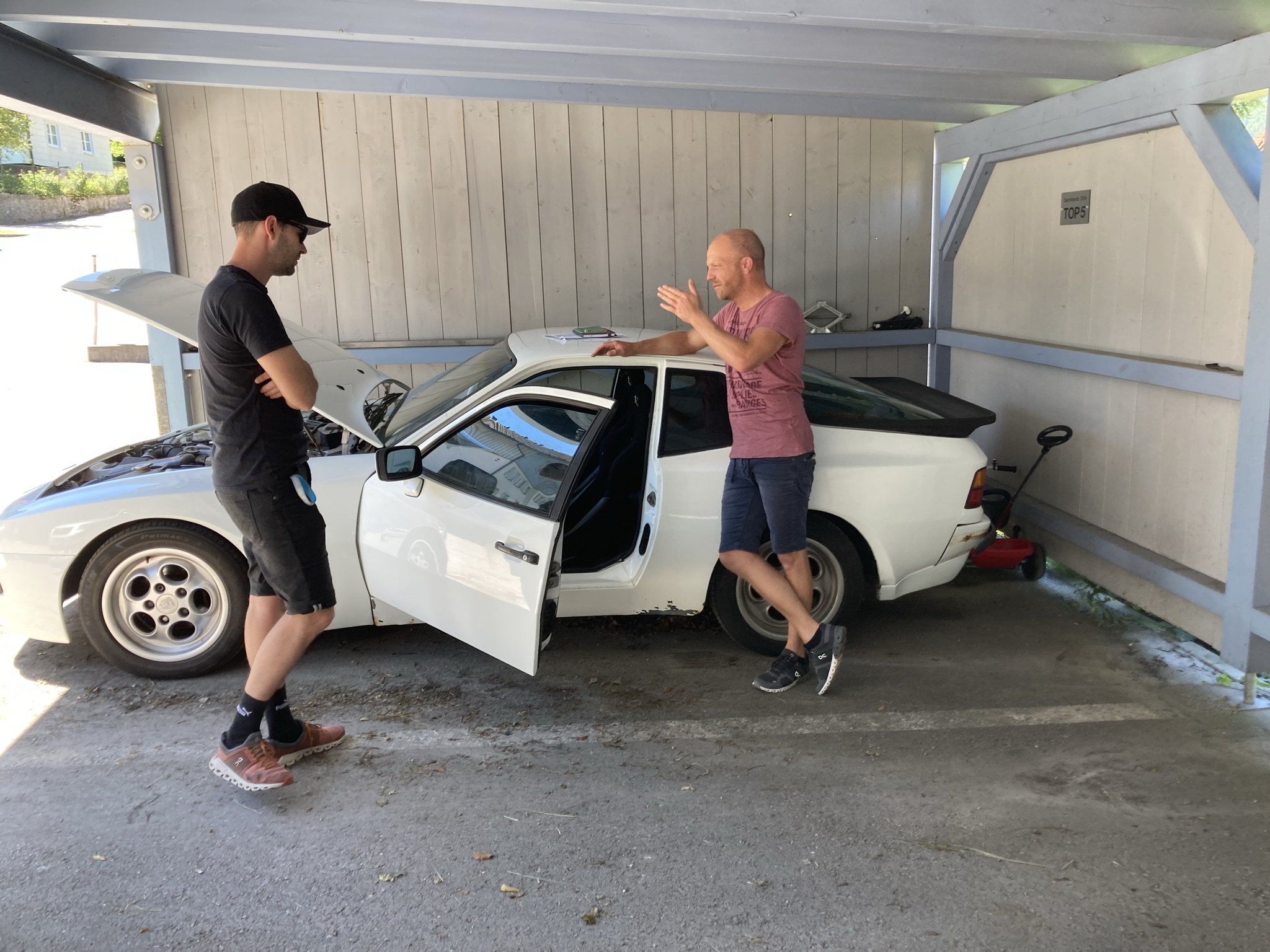 Zwei Garagisti an der offenen Haube eines Porsche 944